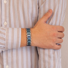 Male model with Blue Moon bracelet resting hand on opposite arm, highlighting bold matte and polished titanium link design.