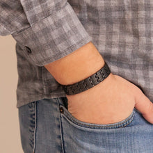 Man wearing the Brilliant Black matte stainless steel bracelet with thumb in pocket, showing understated checkered pattern.