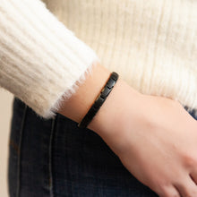 Female model wearing EverStrength bracelet with matte and polished black links, hand near pocket.