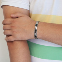 Male model wearing Impact bracelet with cross-shaped spacer links and carbon fiber details, hand resting on opposite arm.