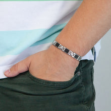 Male model wearing Impact bracelet with carbon fiber inlay and stainless steel links, hand in pocket.