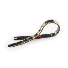 Lineage negative ion bracelet with black stainless steel and gold, unclasped and folded for display.