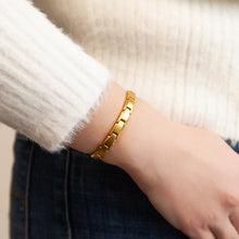 Female model wearing Luminosity bracelet with polished gold borders and matte center.
