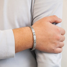 Male model wearing Reflection bracelet showing interlocking matte and polished links with hand resting on opposite arm.