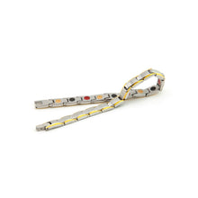SandStorm bracelet unclasped, displaying alternating matte steel and polished gold detailing with embedded elements.