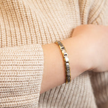 Close-up of SandStorm bracelet on wrist showing dual-tone stainless steel and gold finish.