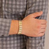 Male model wearing the Mysterious Twist gold and stainless steel bracelet, hand resting on opposite arm to display polished two-tone pattern.