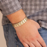 Man wearing the Mysterious Twist gold and stainless steel bracelet with thumb in pocket, showing checkered gold and steel link design.